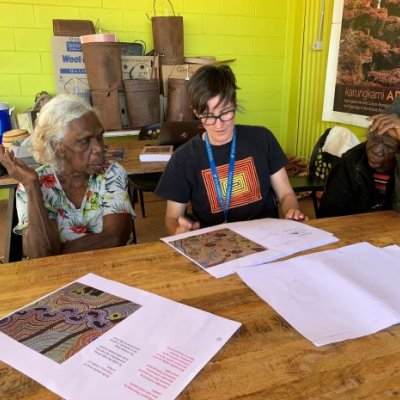 Three people sitting at a table looking at book.